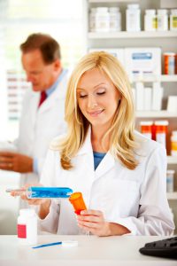 Pharmacist measuring pills into a bottle