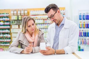 Male friendly pharmacist serving a female customer.