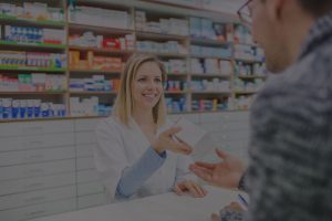 Female pharmacist hands out medication to male patient